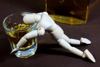 wooden figurine passed out over glass of alcohol